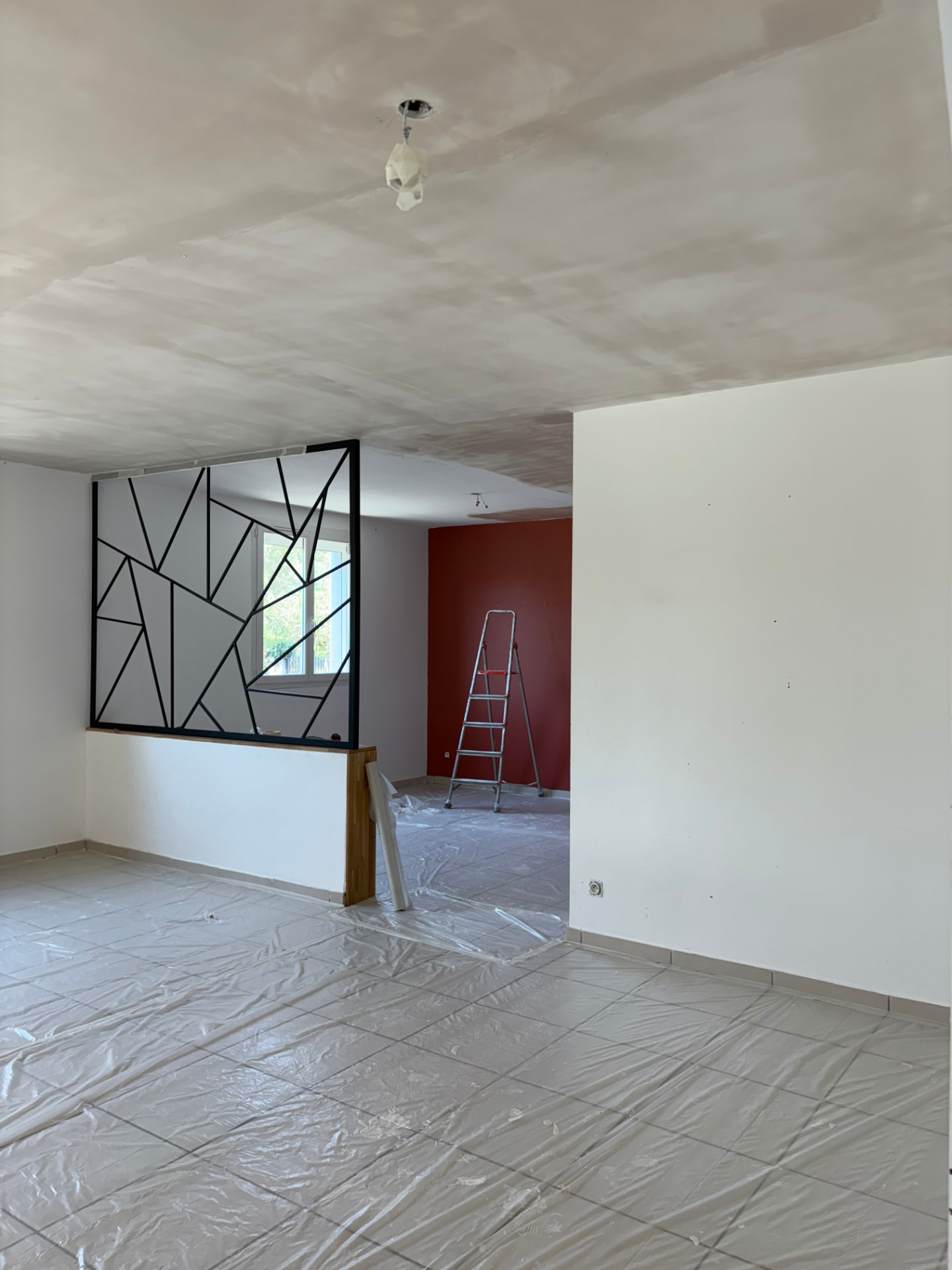 Pièce en cours de chantier, plafond enduit, verrière et mur rouge, sols protégés